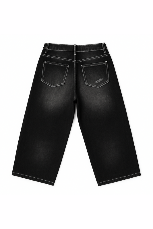 Flat lay of back view of Version Originale’s black Tony Hawk jeans with faded detailing, featuring a subtle skateboard and “1999” print honoring Tony Hawk’s iconic 900 spin at the 1999 X Games