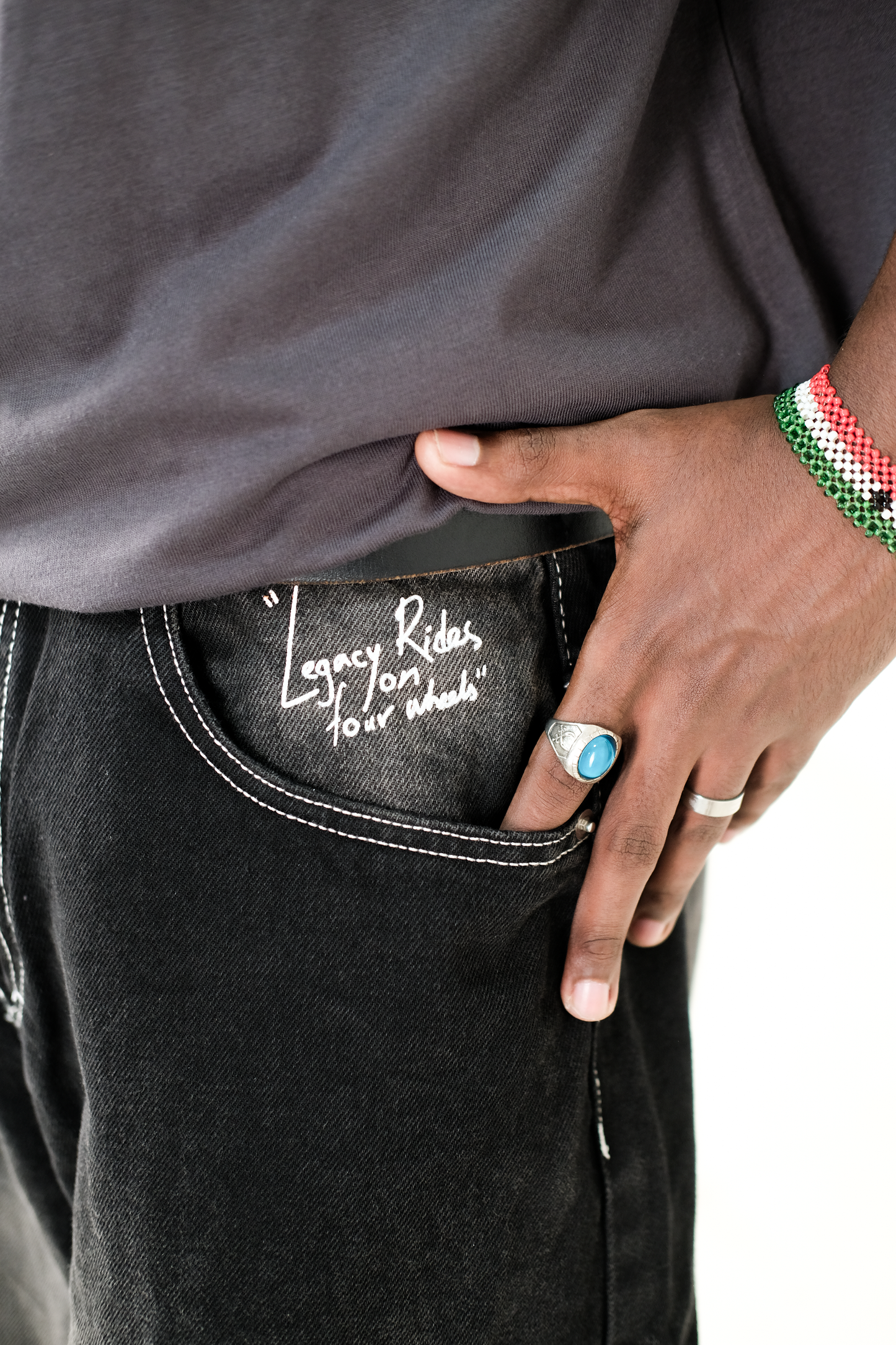 Close-up of a model wearing Version Originale’s black Tony Hawk jeans, highlighting the “Legacy Rides on Four Wheels” print above the pocket