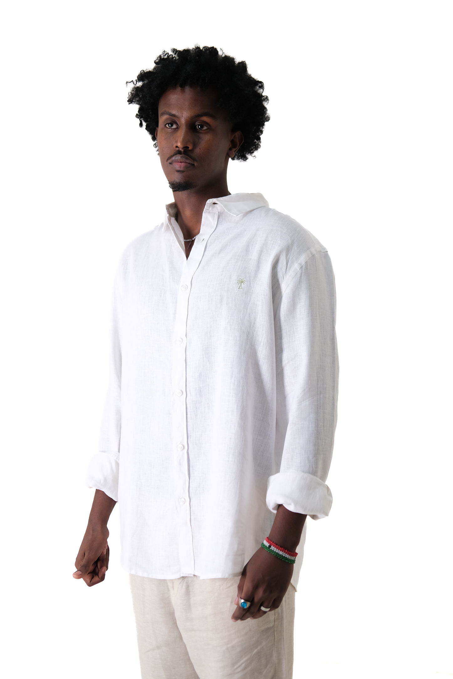 Male model wearing Version Originale's classic white linen shirt with green palm tree embroidery, styled with Version Originale's beige linen pants for a clean and relaxed summer look