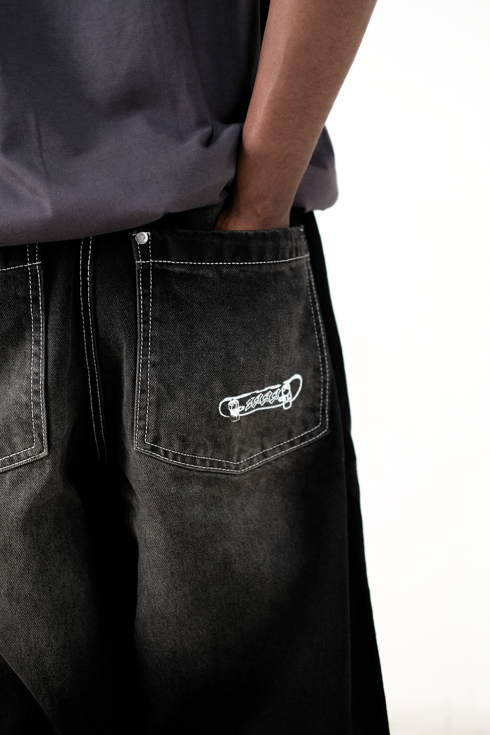 Back view close-up of a model wearing Version Originale’s Tony Hawk jeans, highlighting the skateboard with “1999” print on the pocket, paying tribute to Tony Hawk’s iconic 900 spin at the 1999 X Games