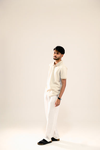 Man wearing a white polo shirt and pants against a plain background