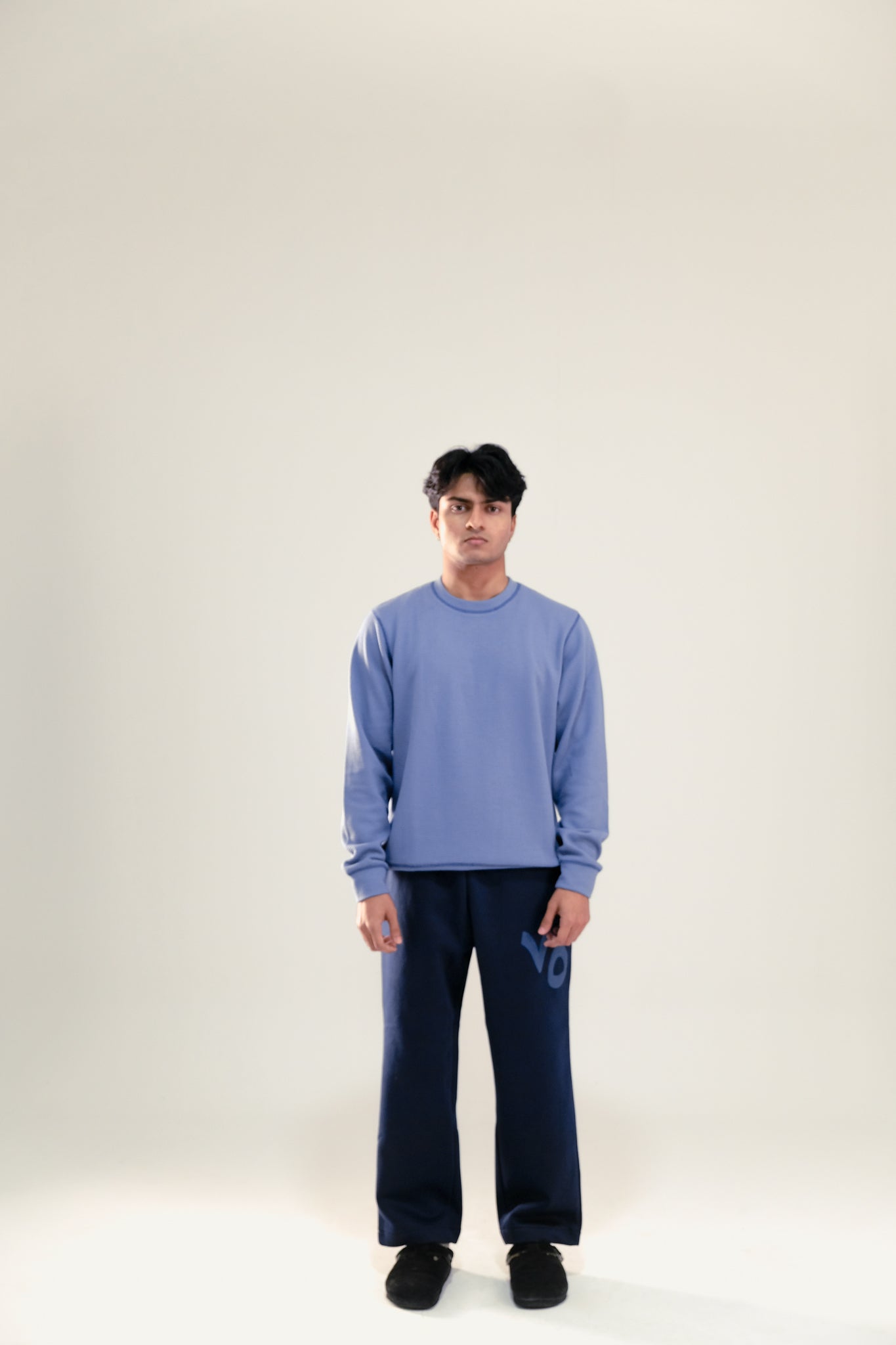 Man wearing blue waffle knit sweatshirt and navy blue sweatpants against a white background