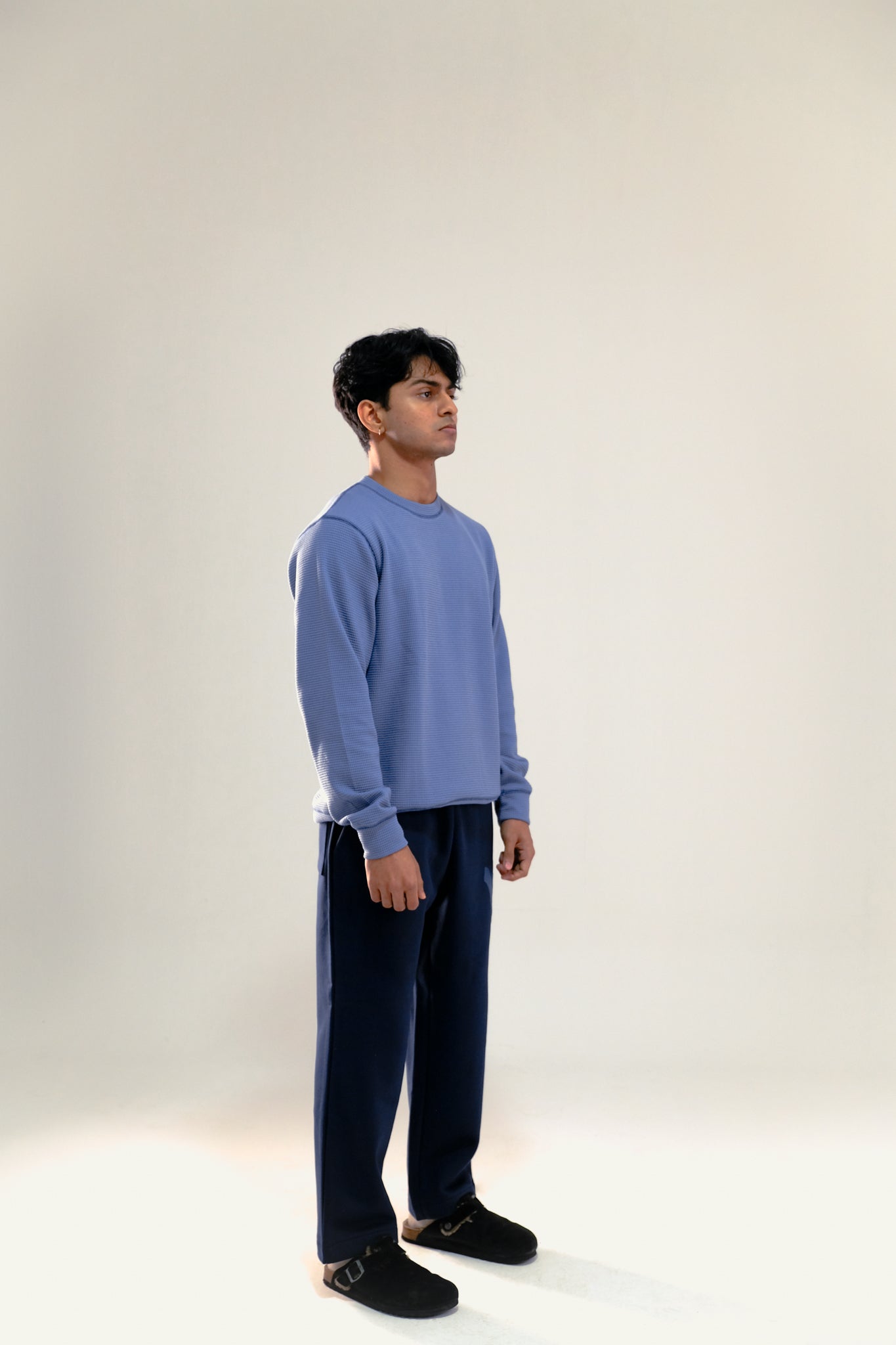 Man wearing blue waffle knit sweatshirt and navy blue sweatpants against a white background