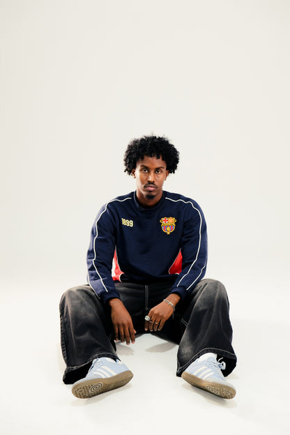 Model wearing Navy blue sweatshirt with Red side panels featuring a vintage Barcelona crest and '1899' embroidery against a white background
