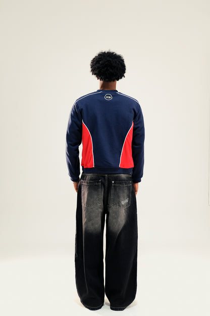 Model facing backwards wearing navy blue and red vintage Barcelona sweatshirt with black baggy jeans against a white background