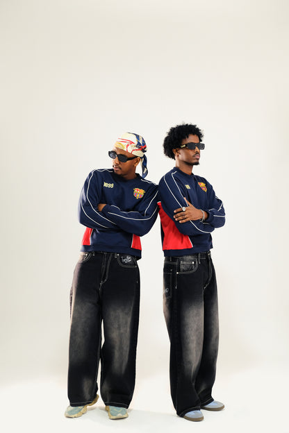 Two models matching outfits wearing vintage Barcelona sweatshirt and baggy washed black jeans and sunglasses against a white background