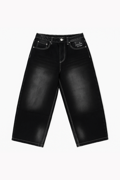 Flat lay of Version Originale’s black Tony Hawk jeans with faded detailing and “Legacy Rides on Four Wheels” print above the left pocket