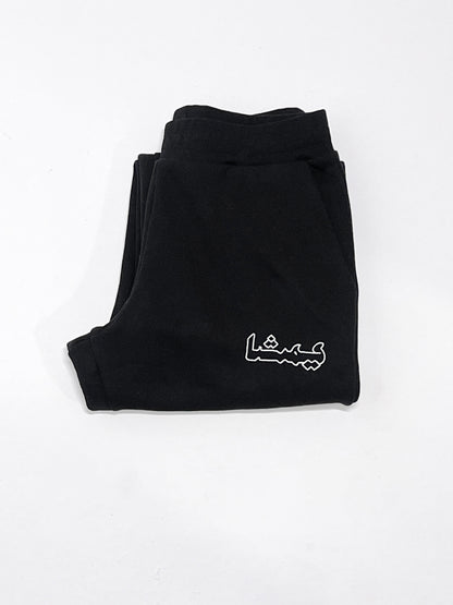 Folded black sweatpants with an arabic print against a white background