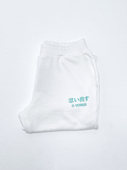 White sweatpants with bright green Japanese text print against a light background