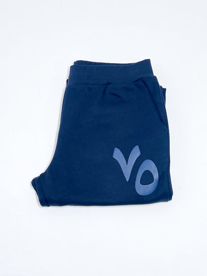 Folded navy blue sweatpants with 'VO' puff print on a white background