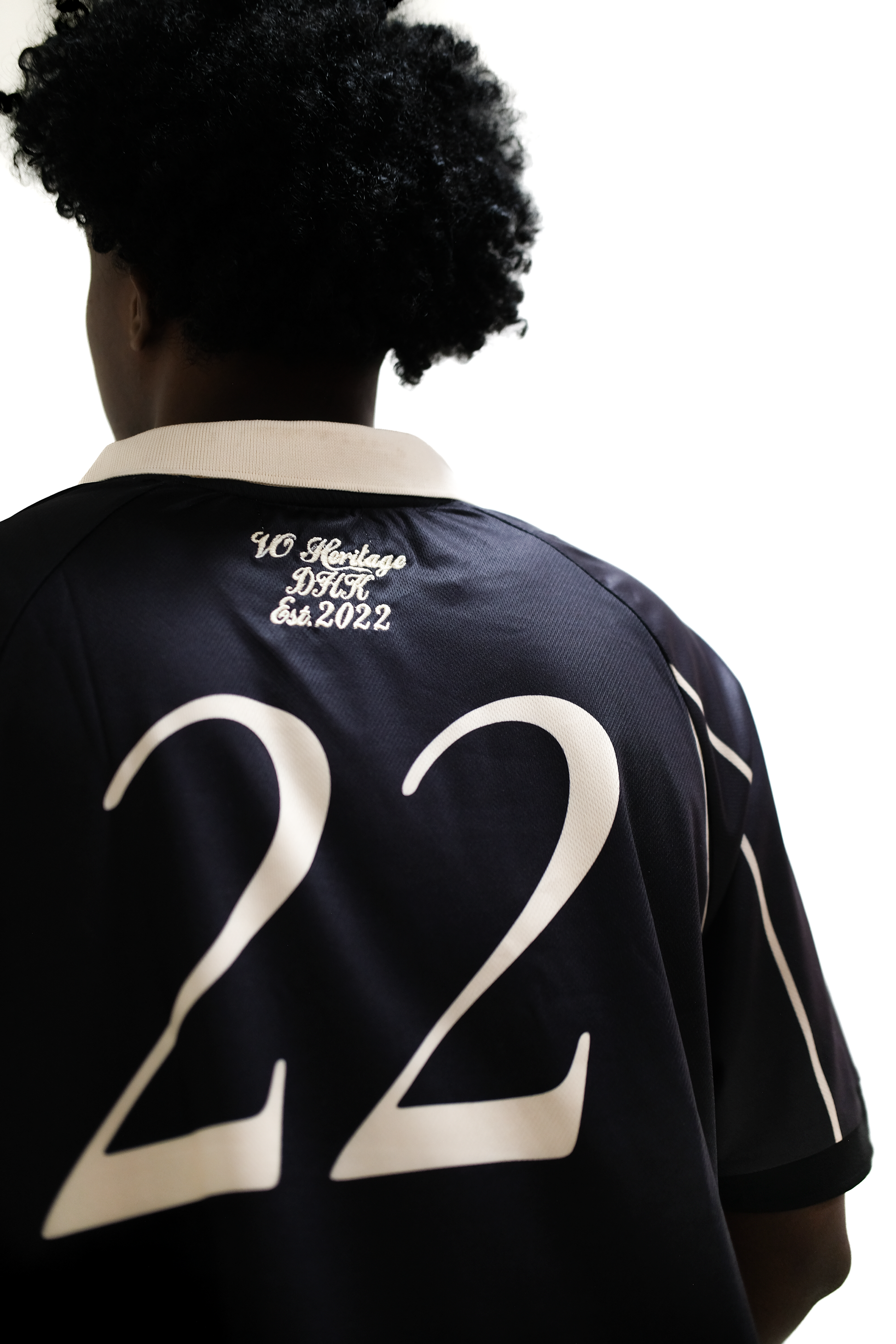Close-up of back view of Version Originale's black athletic jersey with beige number 22, beige piping, and embroidered text ‘VO Heritage DHK Est. 2022’ beneath beige collar