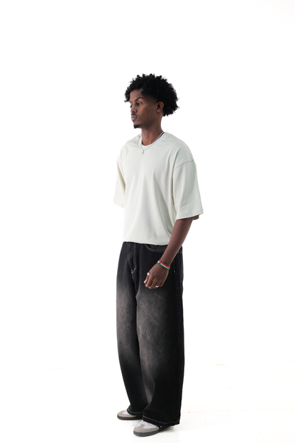 Side view of a male model wearing Version Originale’s oversized lime green tee paired with Version Originale’s baggy faded black denim Tony Hawk jeans